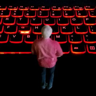 A tiny man stands before an enormous glowing keyboard.