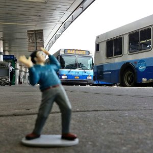 A tiny man is terrified by tremendous mass transit buses.