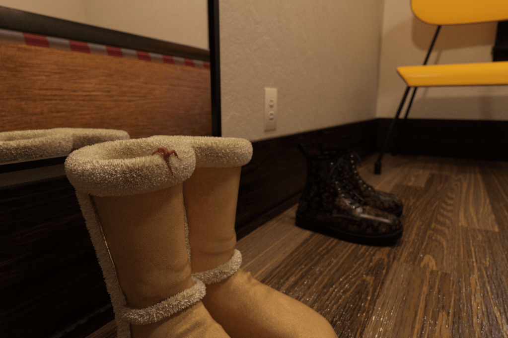 A tiny naked man climbs into a pair of UGG boots.